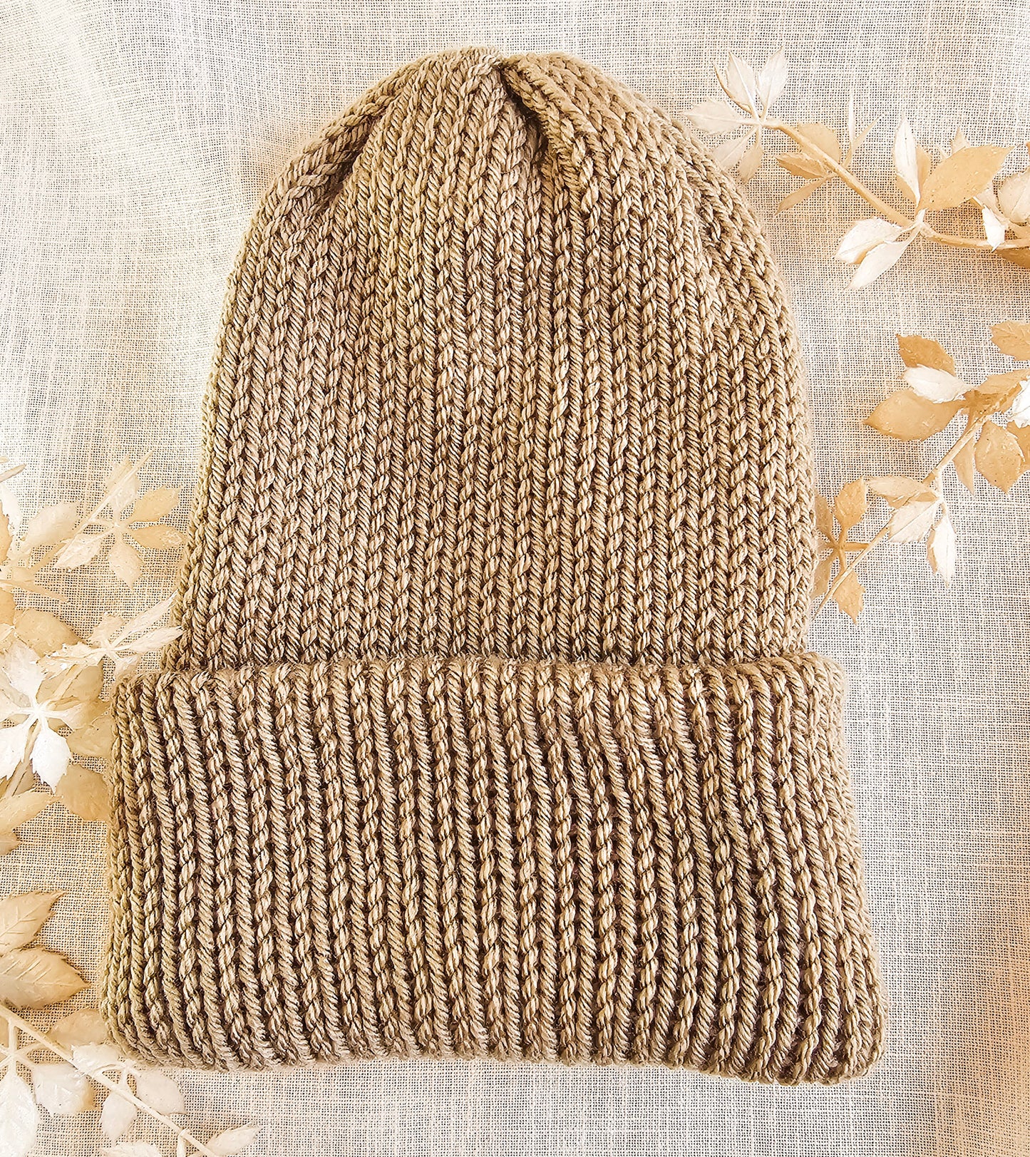 Knitted beanie on a textured fabric background with floral elements