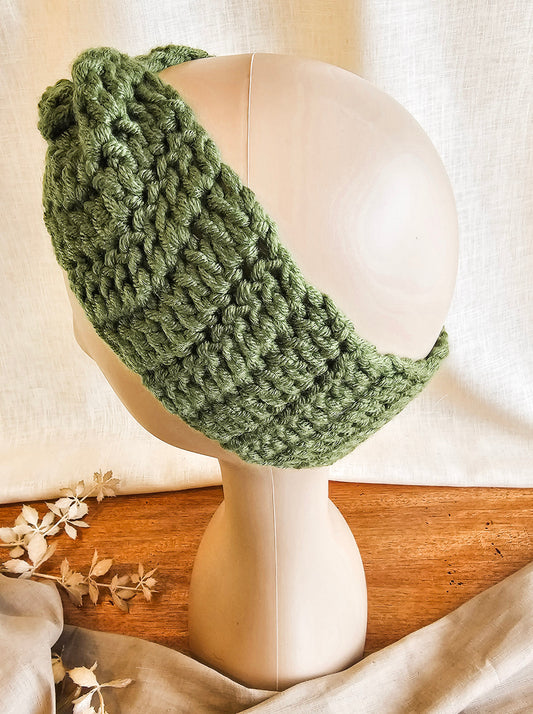 Green knitted headband on a mannequin head with a soft background