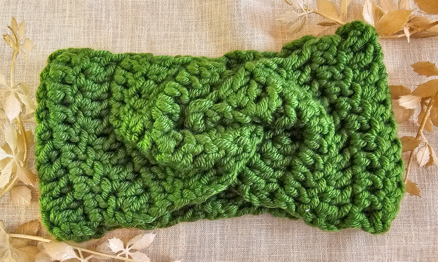Green knitted headband on a textured beige background