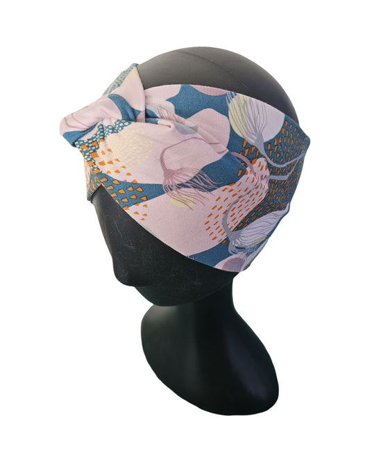 Colorful headband with floral pattern on a black mannequin head against a white background