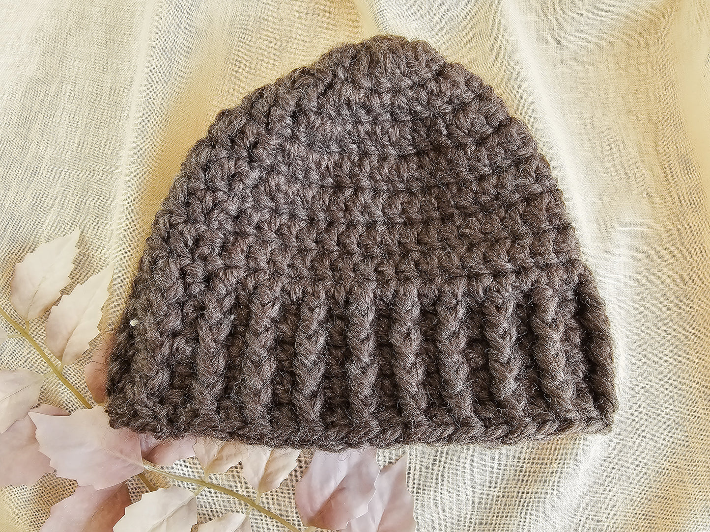 Brown knitted beanie on a light fabric background with floral elements