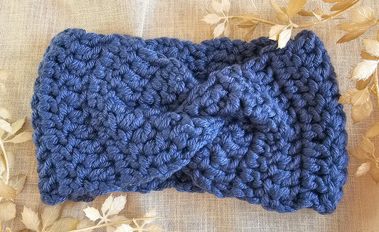 Blue knitted headband on a beige fabric background with gold leaves