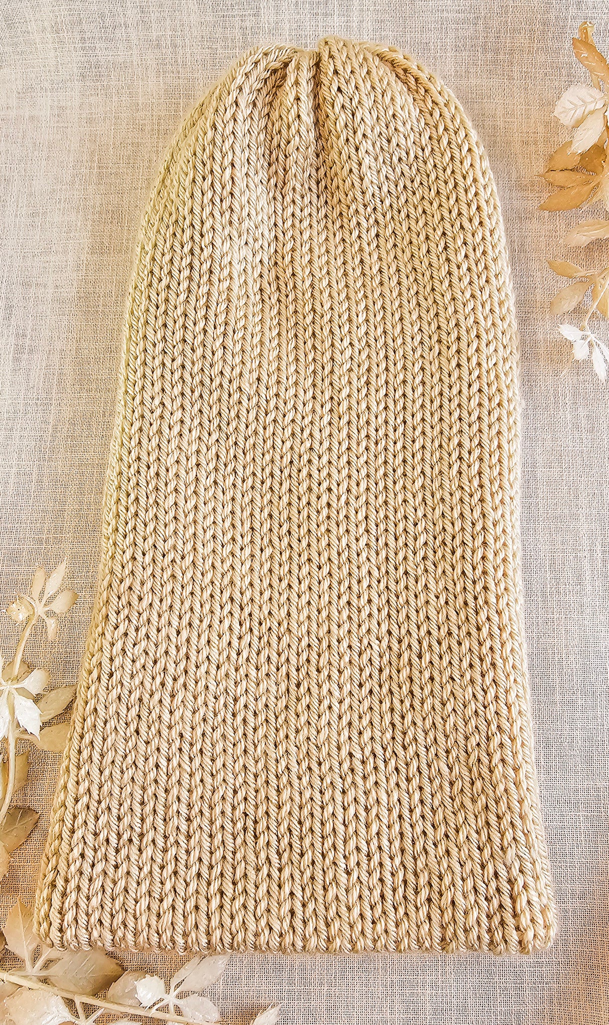 Beige knitted hat on a textured surface with floral decorations