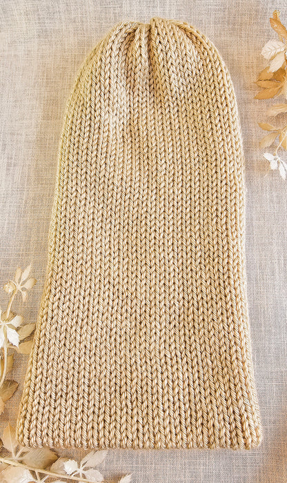Beige knitted hat on a textured surface with floral decorations