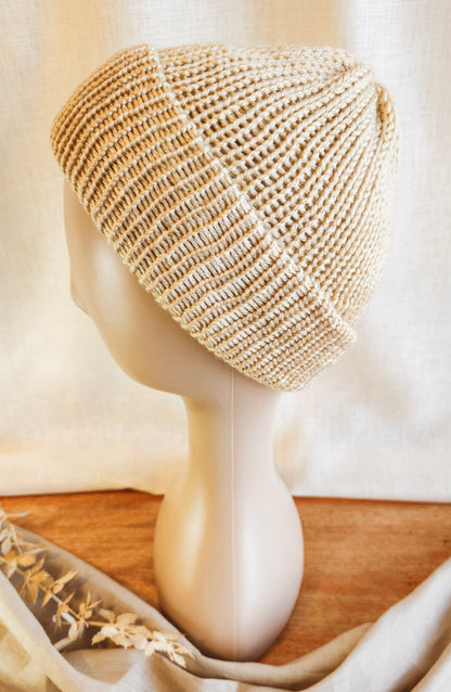 Beige knitted headband on a mannequin head with a neutral background