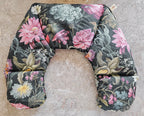Hot and Cold Neck Pack with a dark charcoal background and a detailed floral print featuring pink, white, and green flowers, laid flat on a textured stone surface.