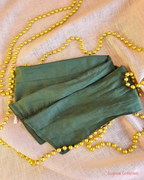 Deck the Halls forest green wire head wrap laid flat on cream fabric with gold Christmas beads.