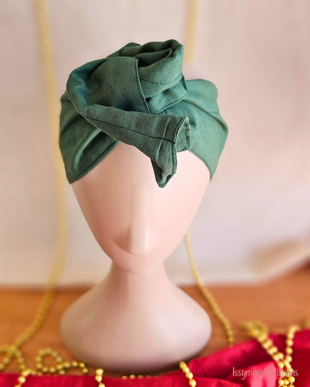 Close-up of the forest green Deck the Halls wire head wrap styled into a twisted rosette on a mannequin.