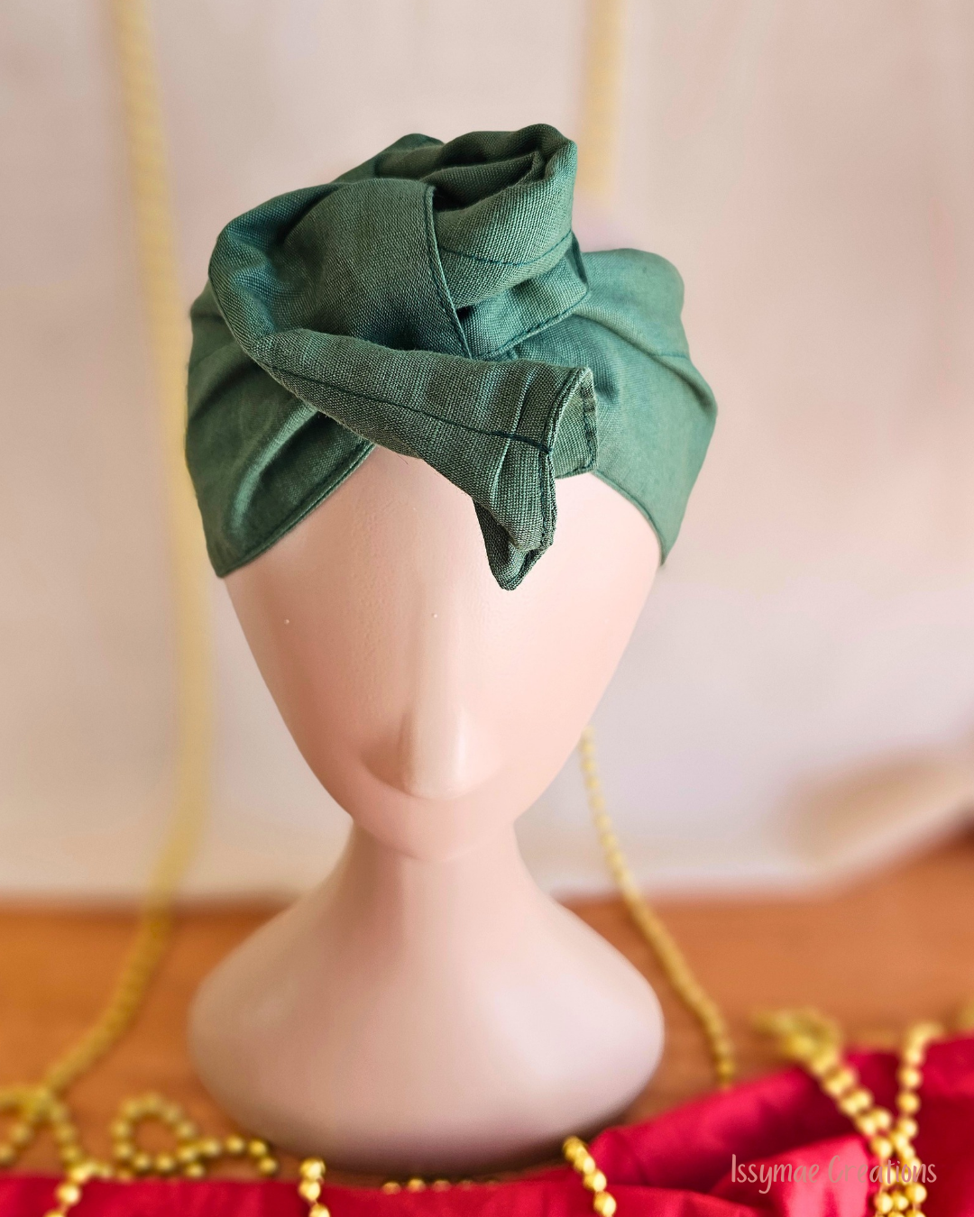 Close-up of the forest green Deck the Halls wire head wrap styled into a twisted rosette on a mannequin.