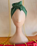Deck the Halls forest green wire head wrap twisted into a tall rosette on a mannequin, front view.