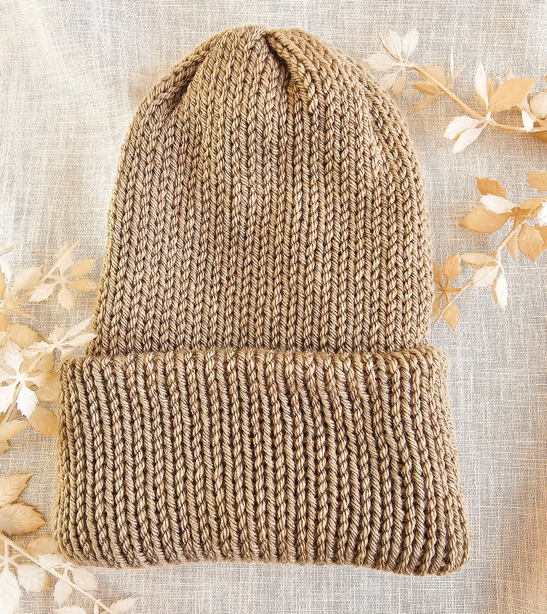 Knitted beanie on a textured fabric background with floral elements