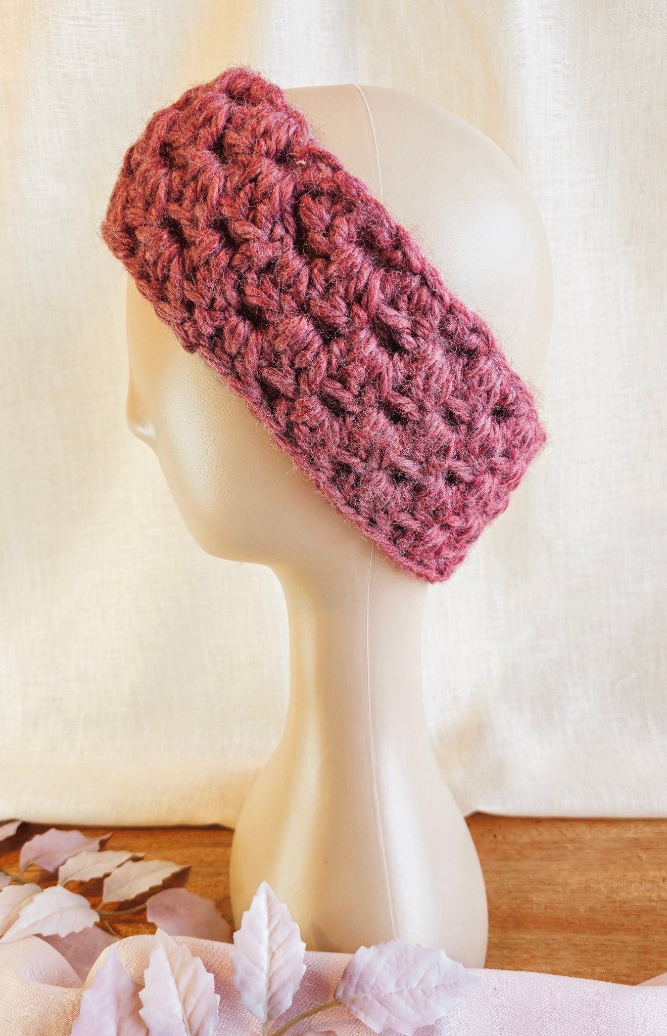 Pink knitted headband on a mannequin head with a soft white background