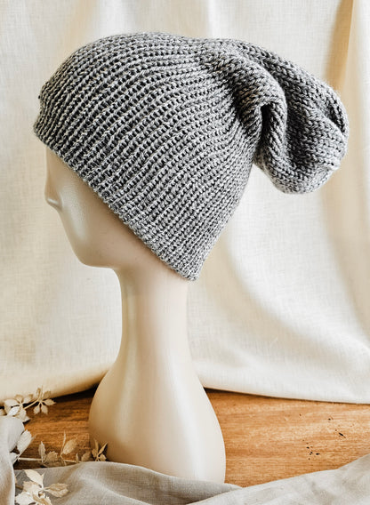 Knitted gray beanie on a mannequin head with a neutral background