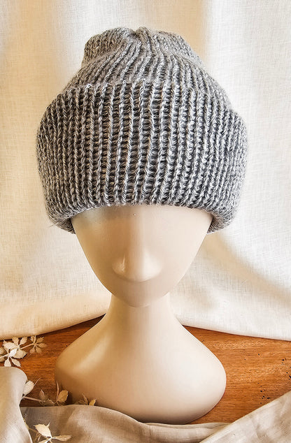 Knitted gray beanie on a mannequin head with a neutral background