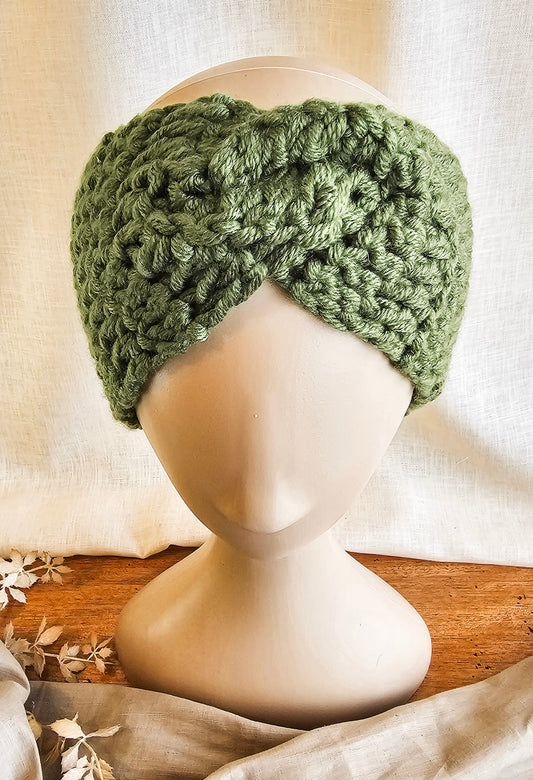 Green knitted headband on a mannequin head with a neutral background