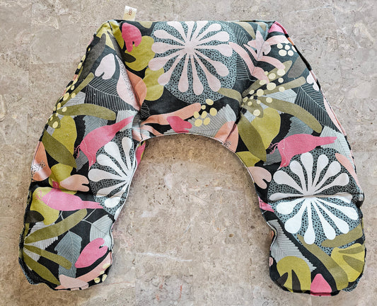 Hot and Cold Pack with a colorful abstract floral and bird pattern, laid flat on a textured stone surface.