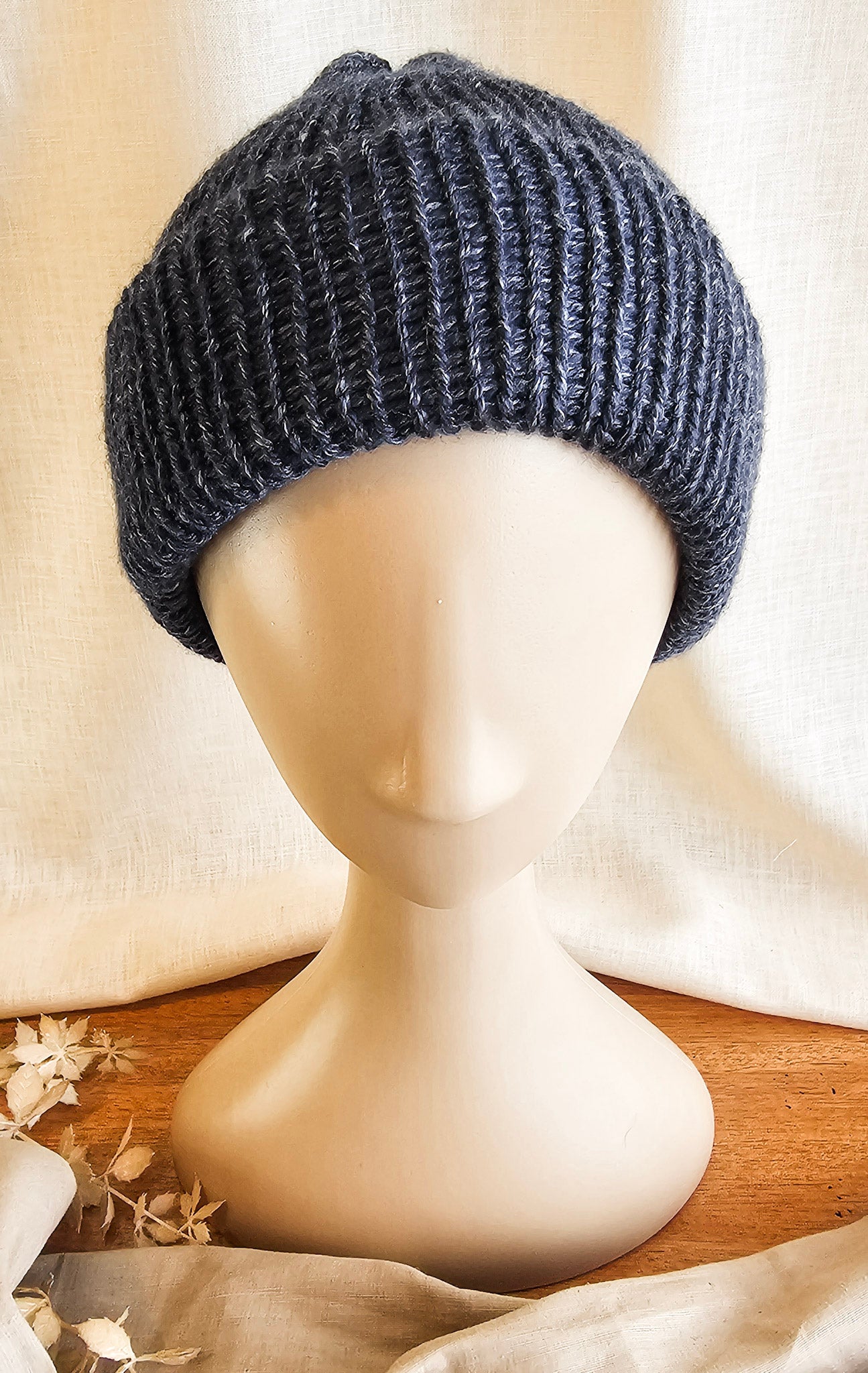 Dark gray knitted beanie on a mannequin head with a neutral background