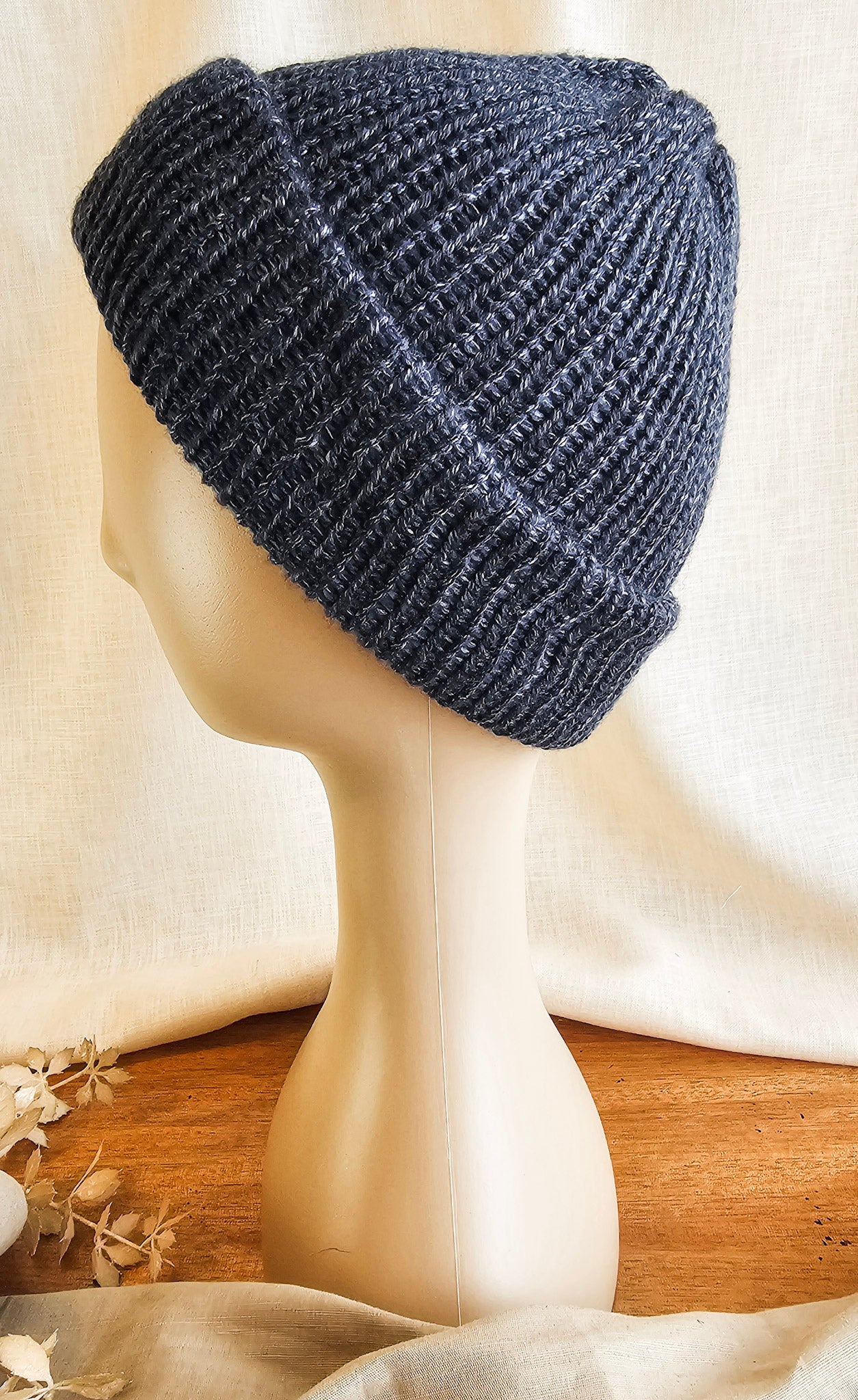 Blue knitted beanie on a mannequin head with a neutral background