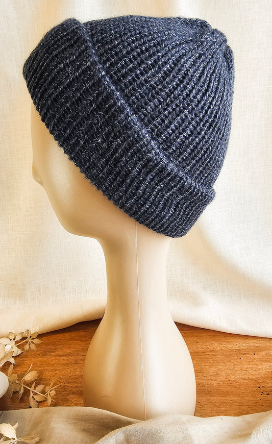 Blue knitted beanie on a mannequin head with a neutral background