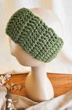 Green knitted headband on a mannequin head with a neutral background