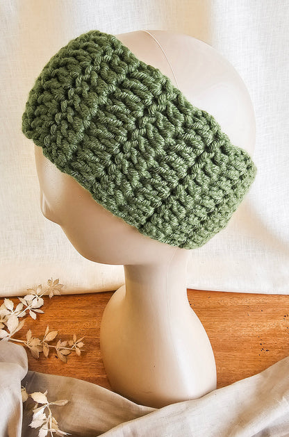 Green knitted headband on a mannequin head with a neutral background