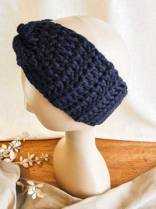 Navy blue knitted headband on a mannequin head with a neutral background