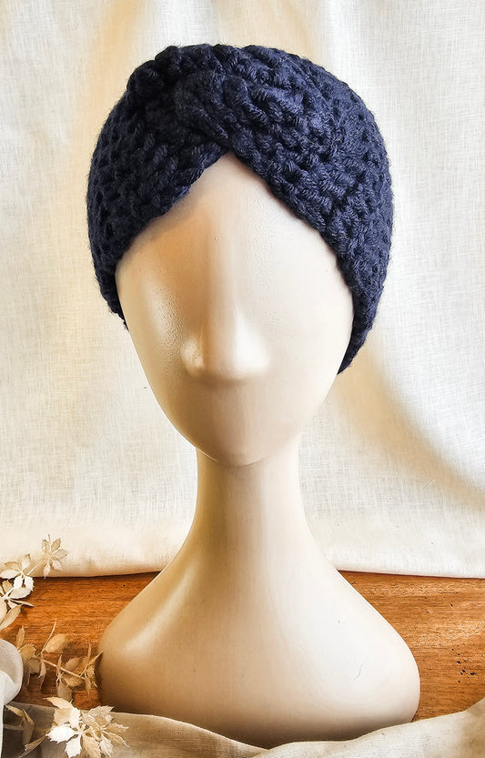 Navy blue knitted headband on a mannequin head against a neutral background