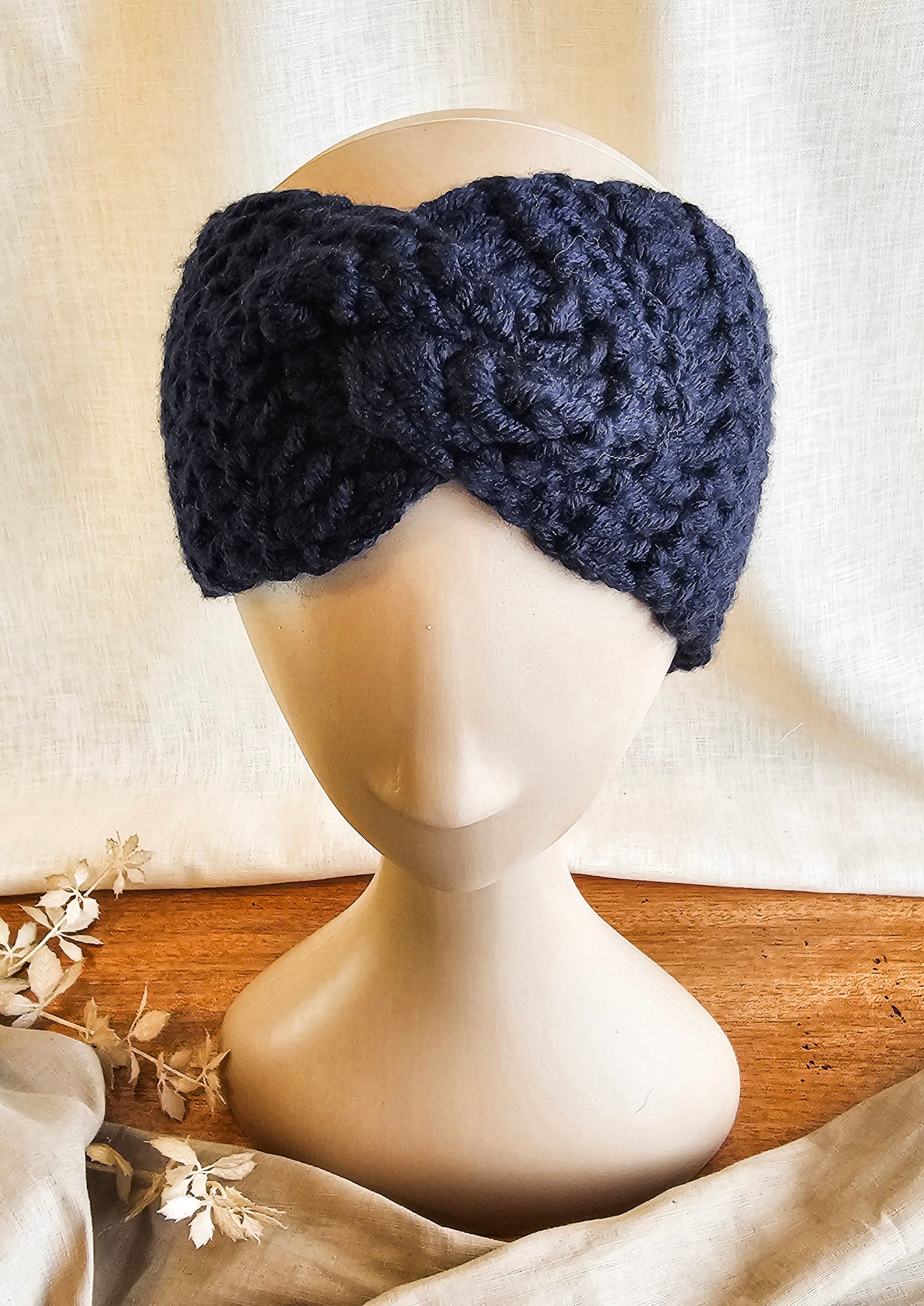 Navy blue knitted headband on a mannequin head with a neutral background