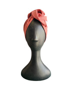Coral headscarf on a mannequin head against a white background
