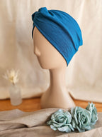 side view of a woman's knotted headband on white head mannequin with soft linen background