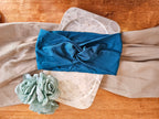 flat view of a teal knotted headband of stone and linen background