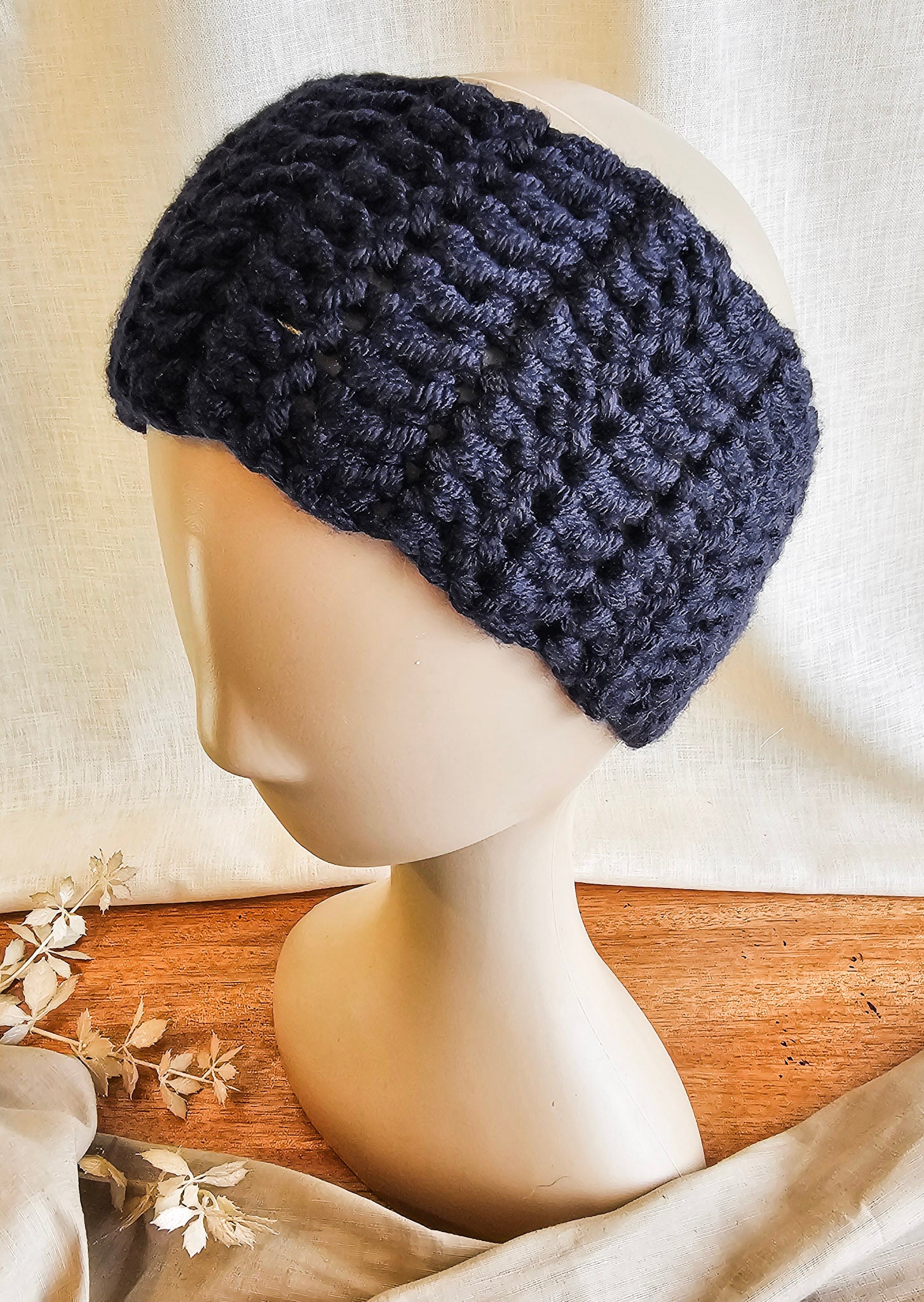 Navy blue knitted headband on a mannequin head with a neutral background