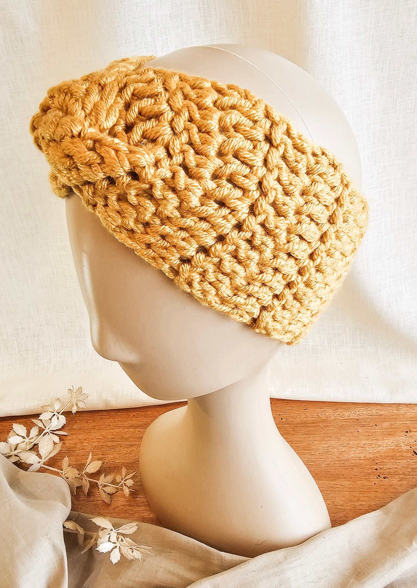 Knitted beige headband on a mannequin head with a white background