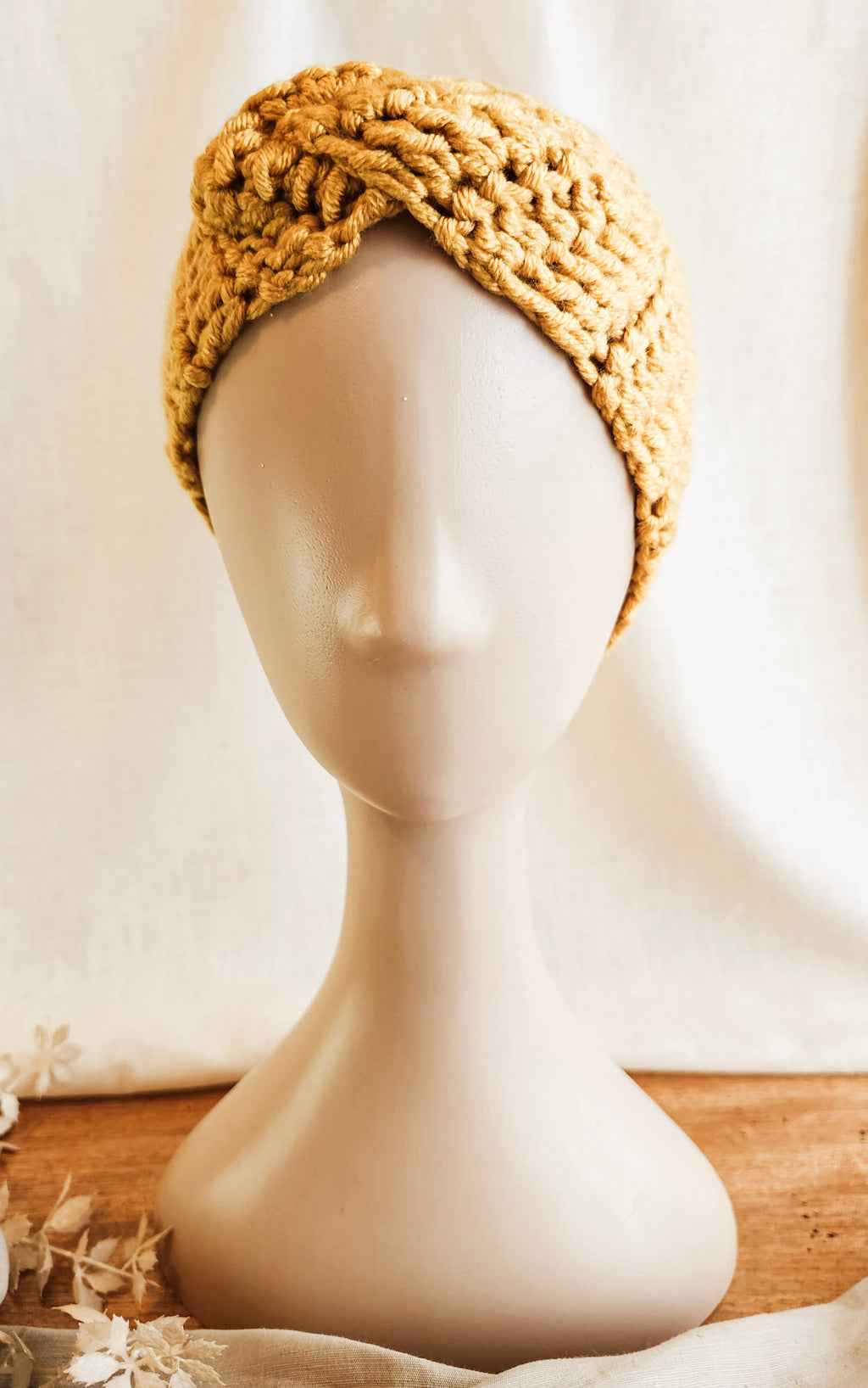 Knitted headband on a mannequin head with a plain background
