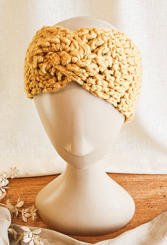 Beige knitted headband on a mannequin head with a neutral background