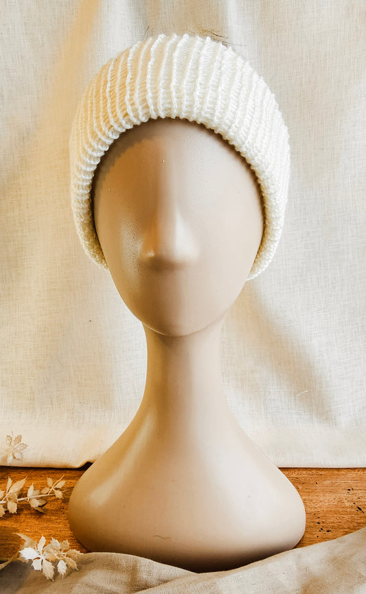 White knitted beanie on a mannequin head against a neutral background