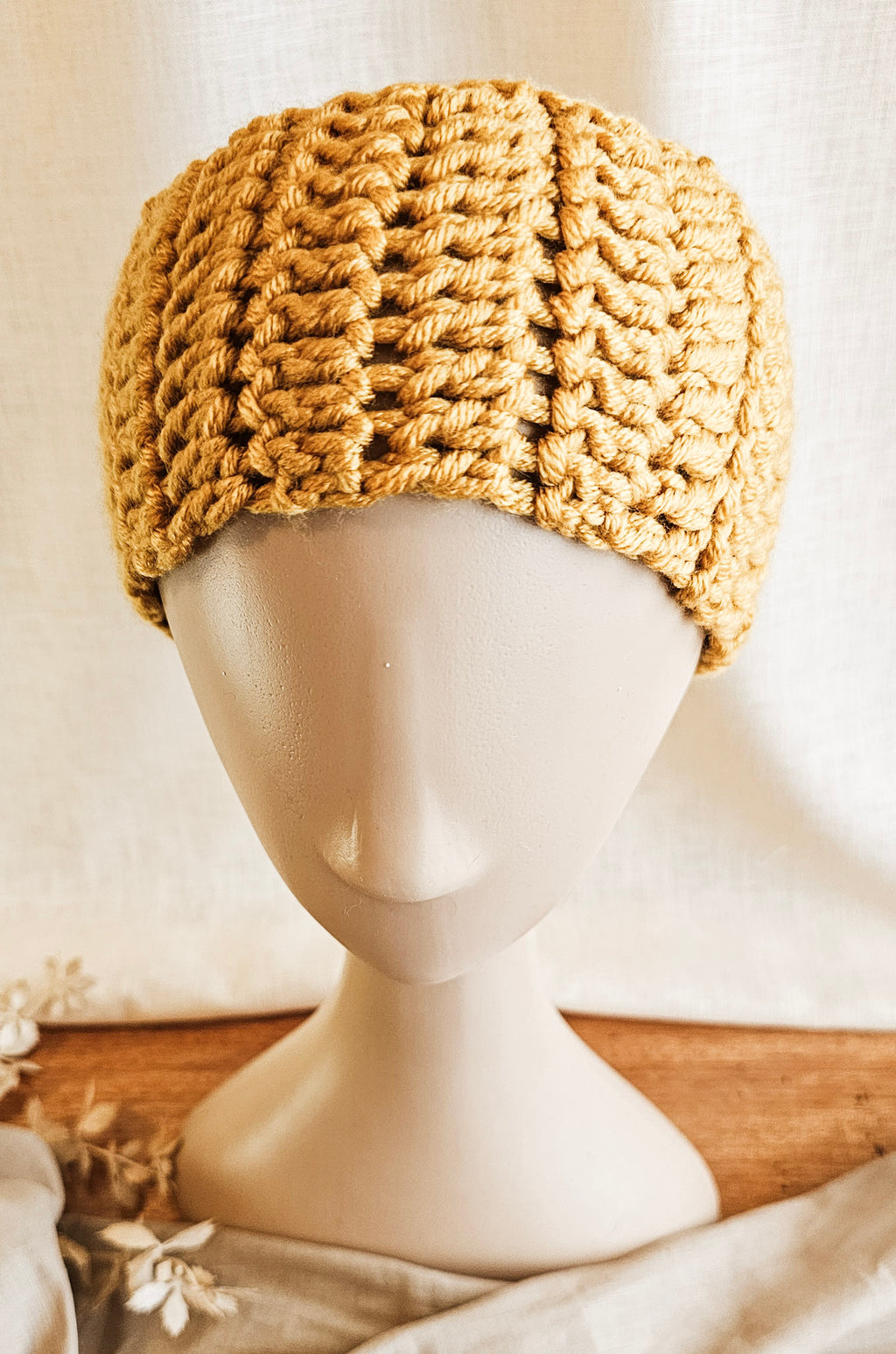 Knitted beige headband on a mannequin head against a neutral background