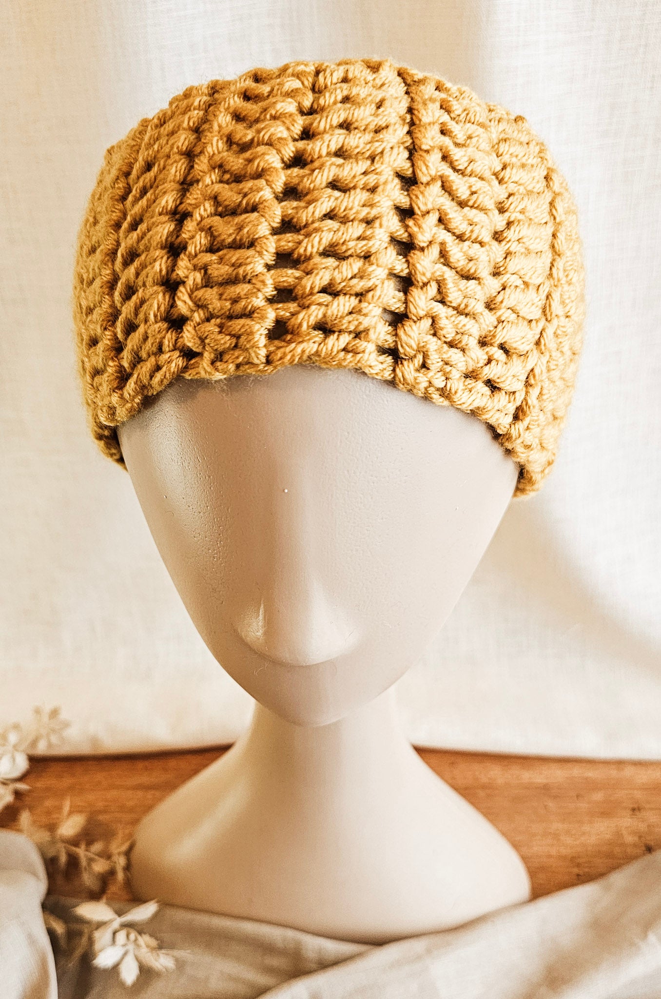 Knitted beige headband on a mannequin head against a neutral background