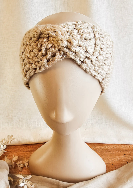 Beige knitted headband on a mannequin head with a neutral background