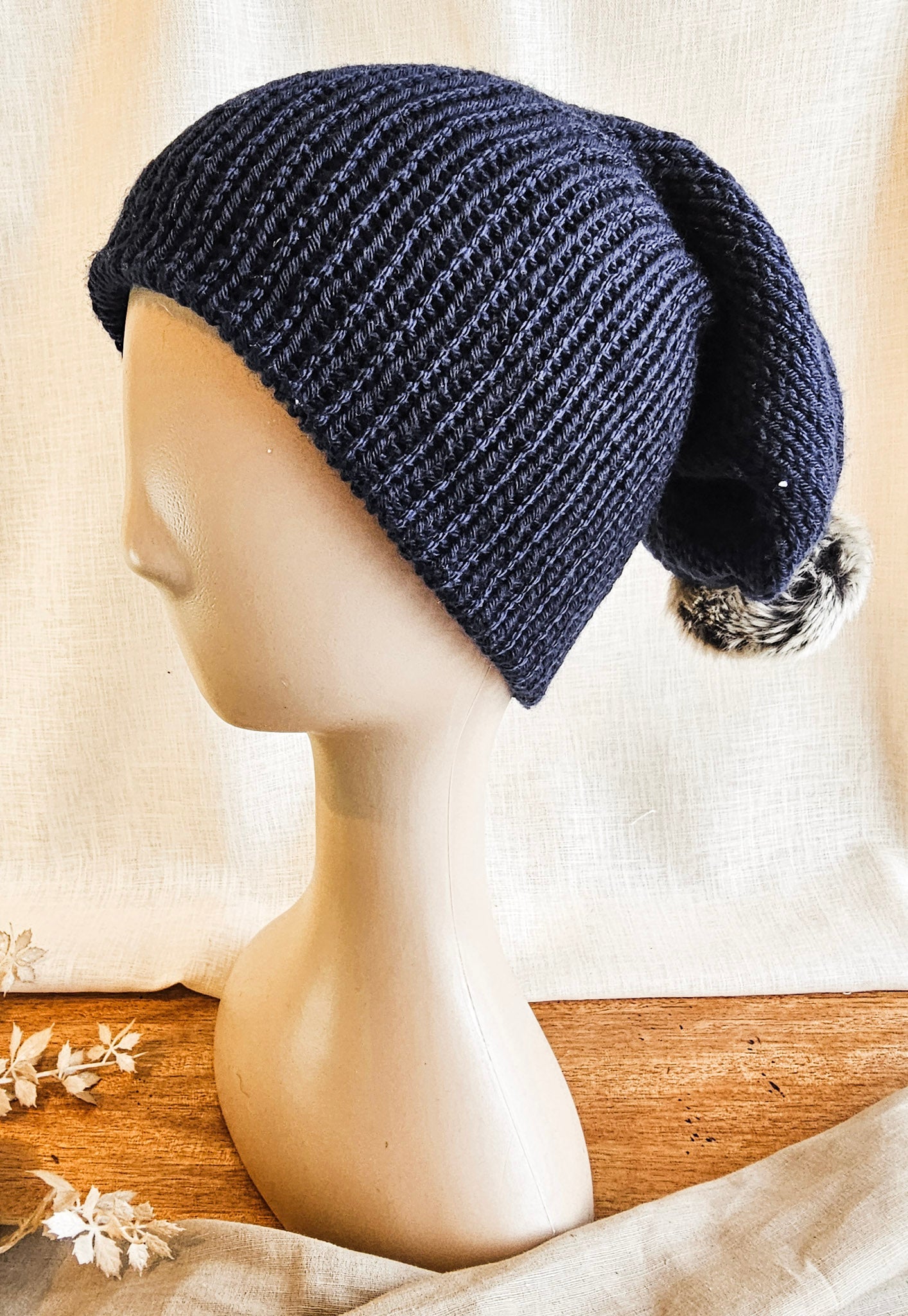 Navy blue knitted beanie on a mannequin head with a white background