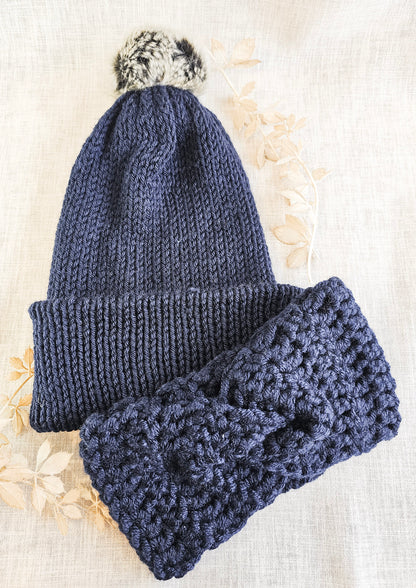 Navy blue knitted hat and headband set on a textured beige background