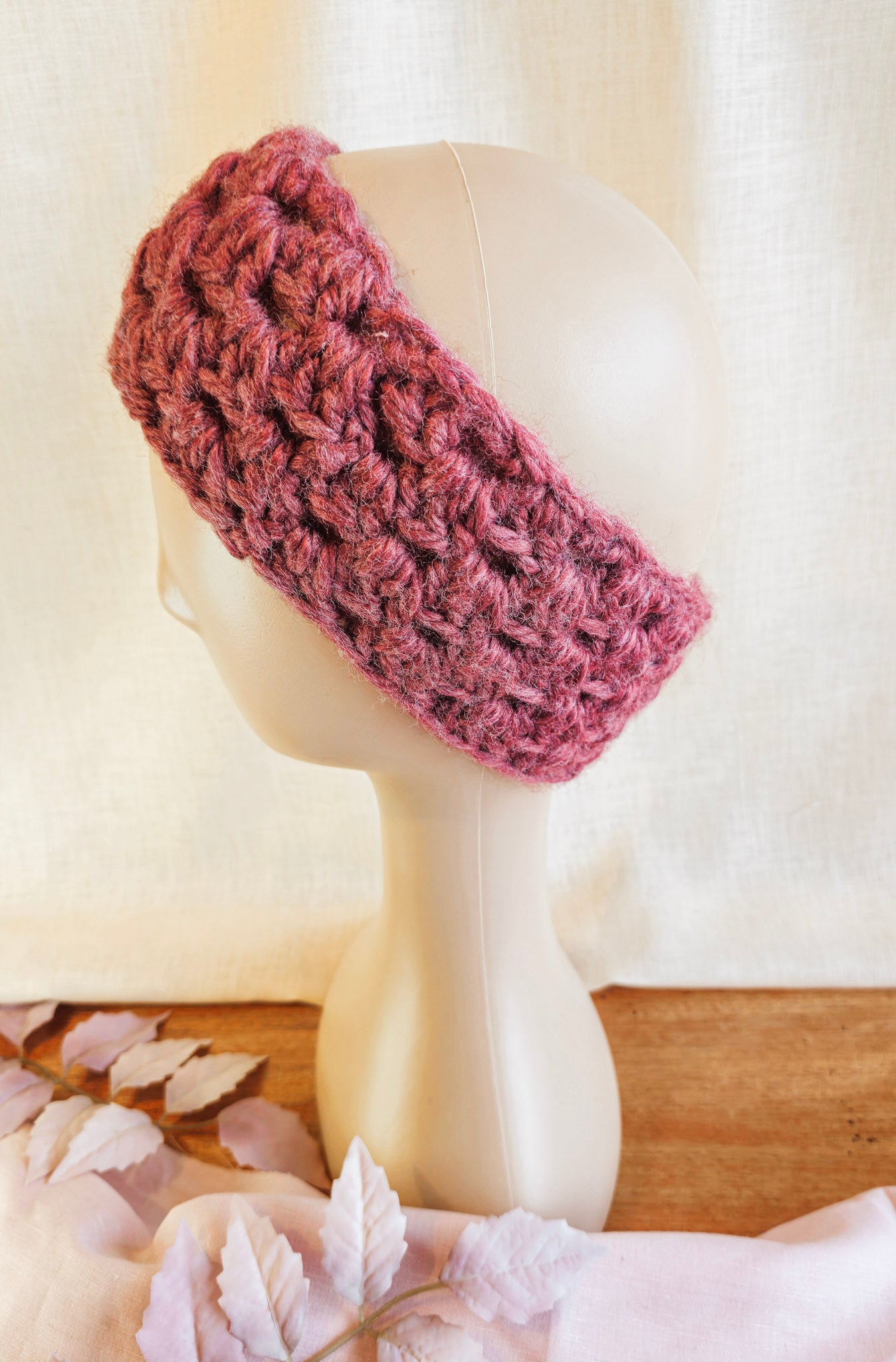 Pink knitted headband on a mannequin head against a white background