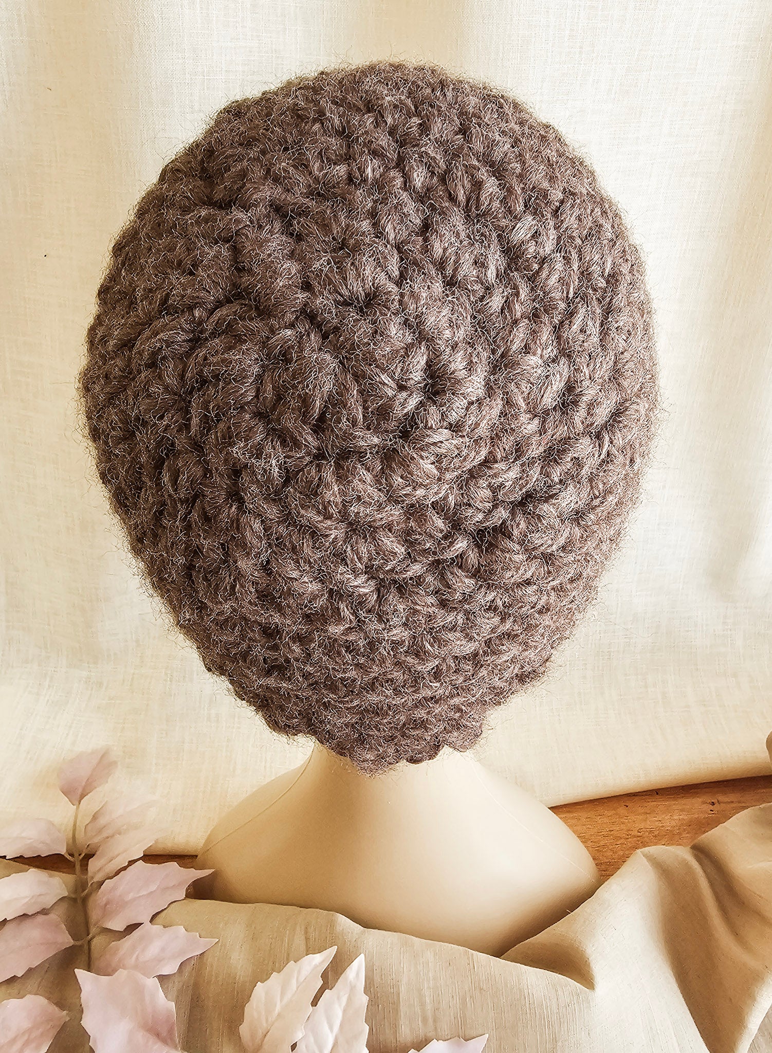 Brown knitted beret on a mannequin head against a neutral background