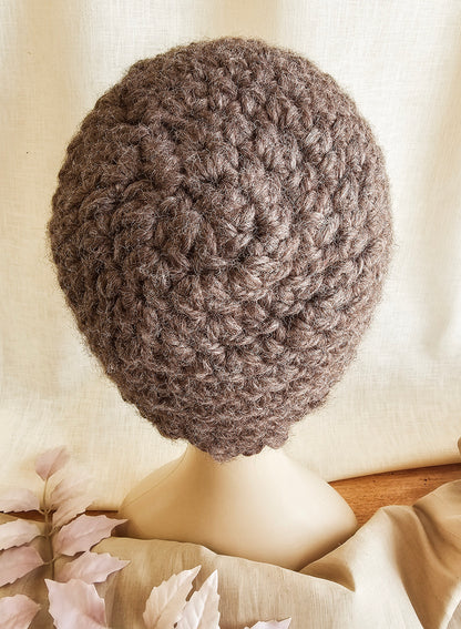 Brown knitted beret on a mannequin head against a neutral background