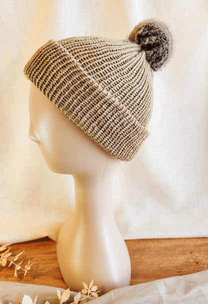 Knitted beanie with pom-pom on a mannequin head against a white background