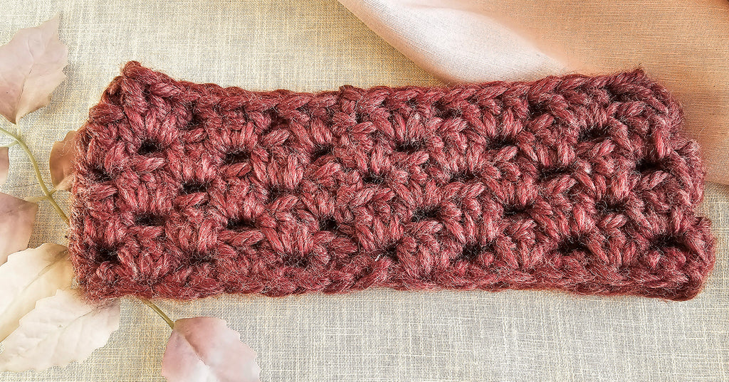 Crocheted headband in pinkish-brown on a textured beige background