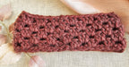 Crocheted headband in pinkish-brown on a textured beige background