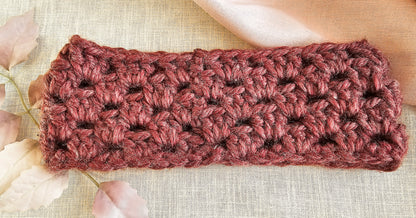 Crocheted headband in pinkish-brown on a textured beige background