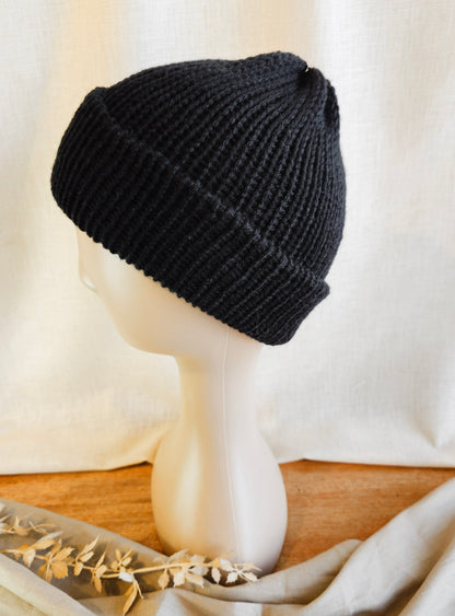 Black knit beanie on a mannequin head with a neutral background
