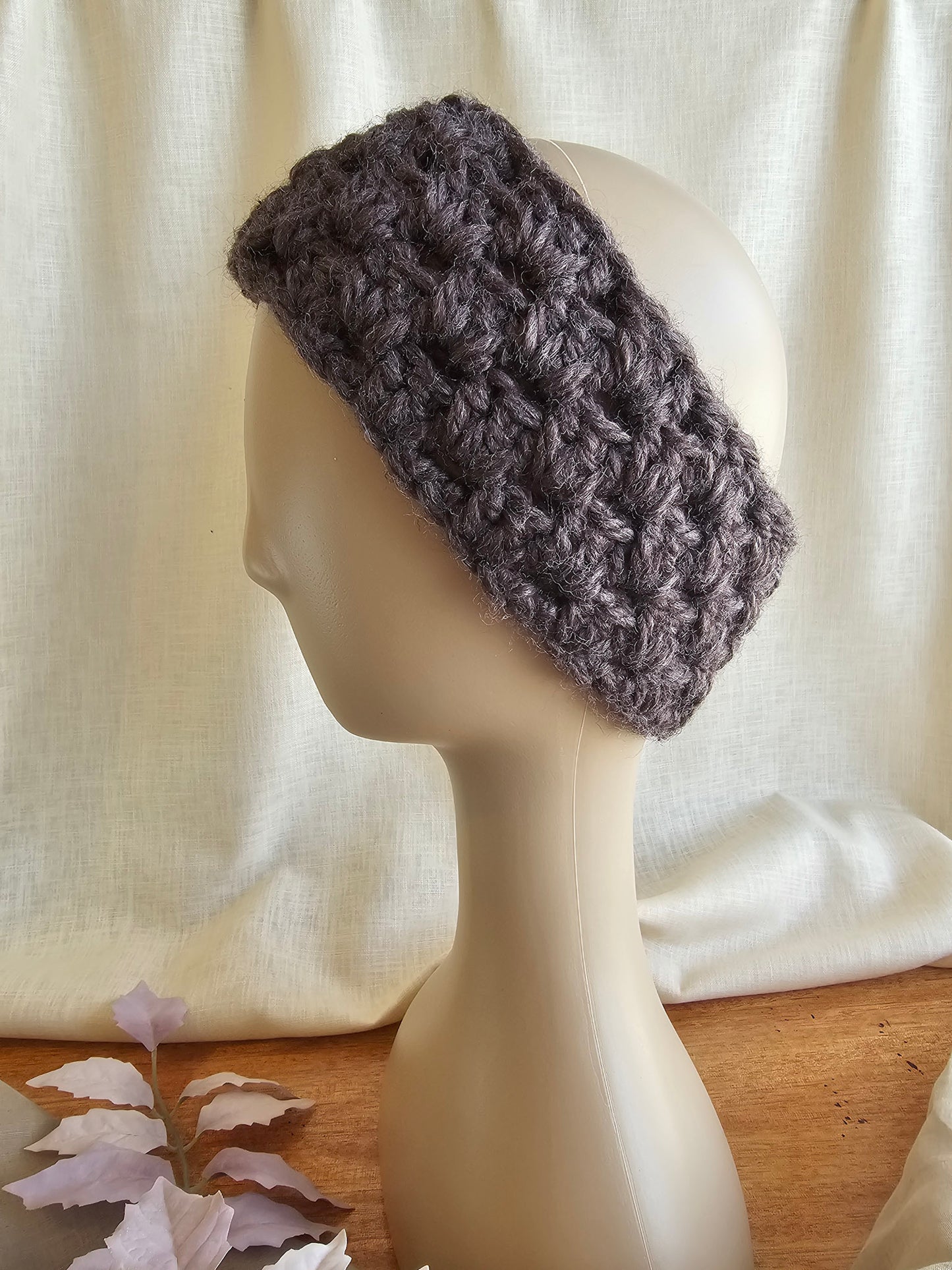 Gray knitted headband on a mannequin head against a white curtain background